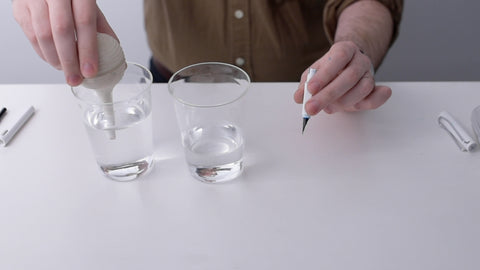 Filling the bulb syringe from one of two water glasses on a table