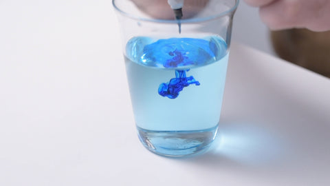 Blue ink swirling in a glass of water