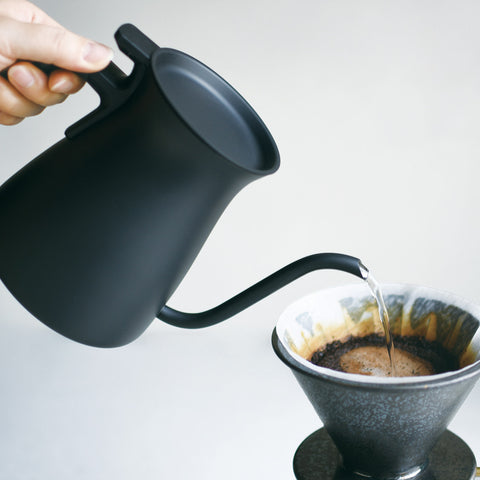 Tipping water from a Kinto Pourover Kettle into a filter full of coffee