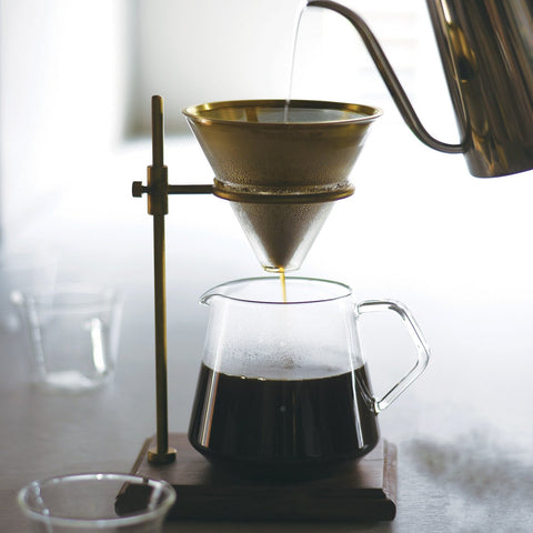 Coffee dripping slowly and majestically through the Kinto SCS Brass Pourover Coffee Stand Set, filling the glass jug at the base with dark rich coffee