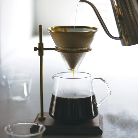 Kinto's Slow Coffee Style Brass Brewer Set sat on a bench, brewing a batch of dark, rich coffee
