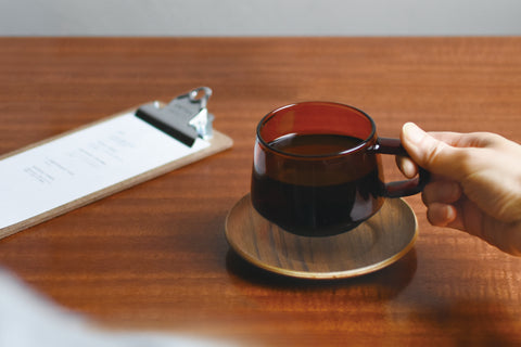 A Kinto Sepia mug, held gently by the handle