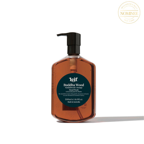 Leif's Buddha Wood hand wash, in a translucent bottle with dark amber liquid inside behind a circular, deep green label with Leif printed in white
