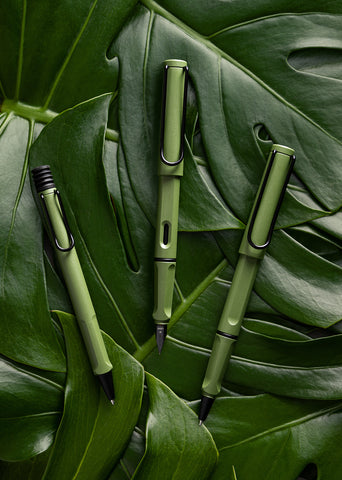 safari Anniversary pens in savannah green finish laid on a bed of monstera leaves