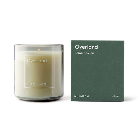 Studio Milligram's Overland Scented Candle [img: a candle in a translucent glass cylinder stands next to a green cubic box with 'Overland' written on the front in a subtle white typeface]