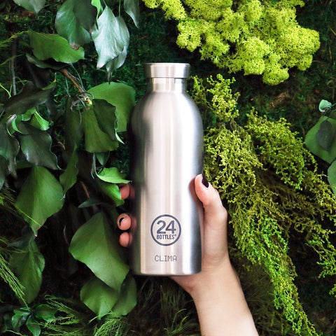24Bottles' Stainless Steel drink bottle, held in front of lots of leafy plants