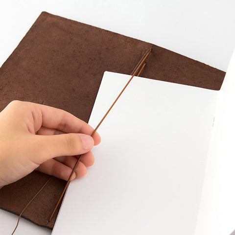 A hand putting a refill into a Traveler's Notebook cover