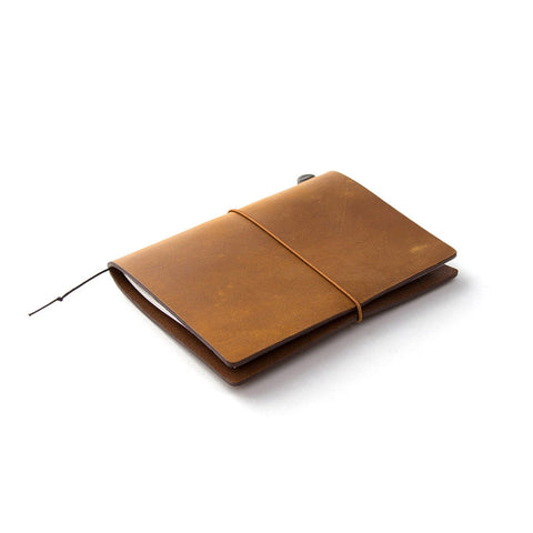 A Traveler's Notebook with Camel coloured leather cover (a rectangular leather outer secured by an elastic band)