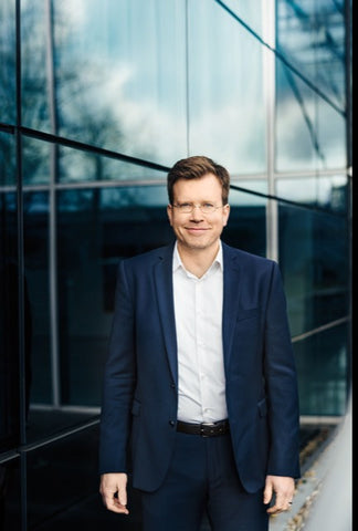 LAMY's Marco Achenbach, a white man with neat brown hair and light glasses. He wears a navy suit with an open-collared white shirt