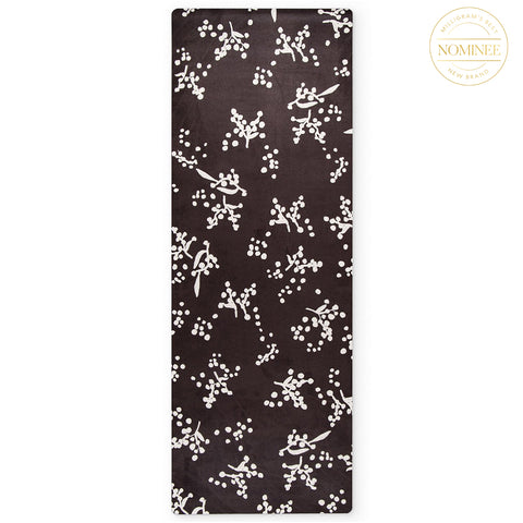 A yin yoga mat in the Watl print, which features plantlike white forms on black background