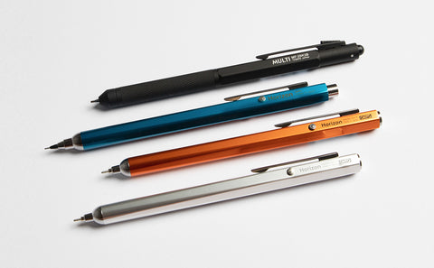img: four OHTO pens laid parallel; one black, one blue, one orange, one silver