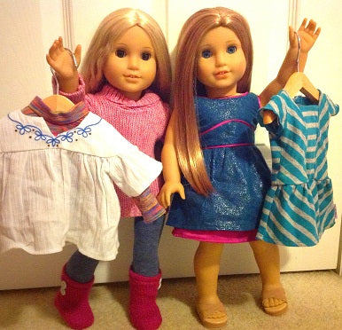 American Girl Dolls holding hangers