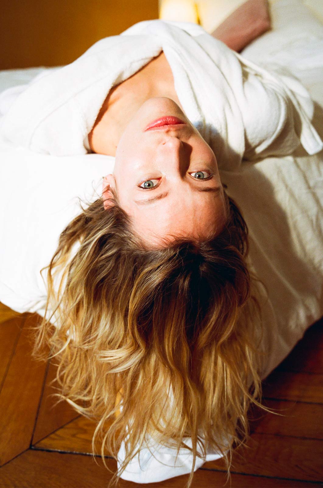 woman lying on the edge of a bed with her hair hanging down