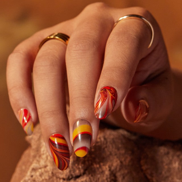 Close up of nails with swirls of red, yellow and brown