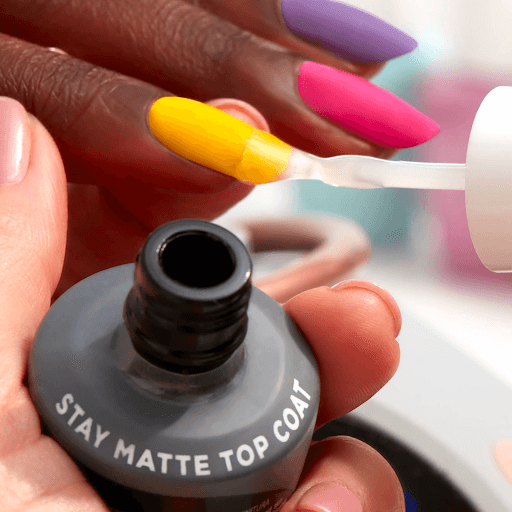Applying matte top coat to yellow nails