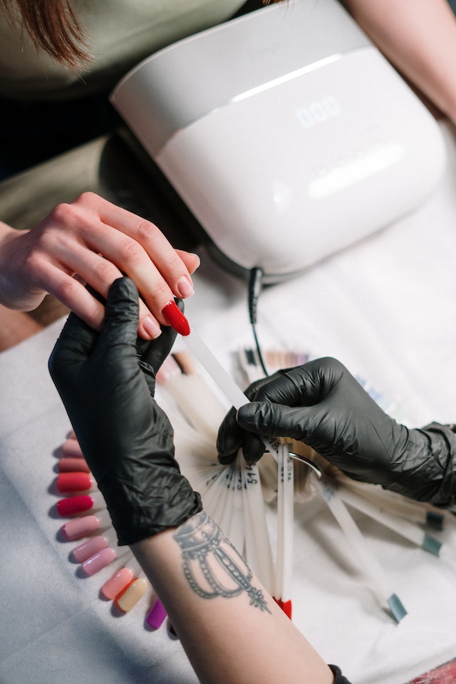 Person with black gloves choosing nail color