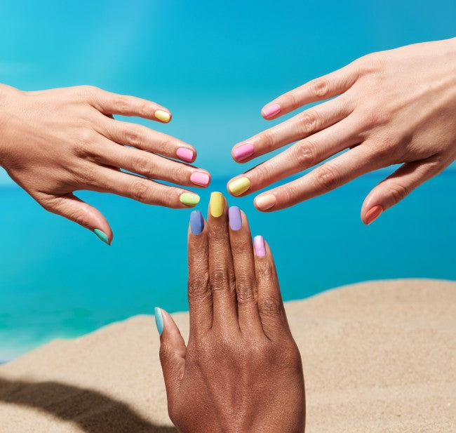 Three hands of varying complexions meet to show up colorful nails