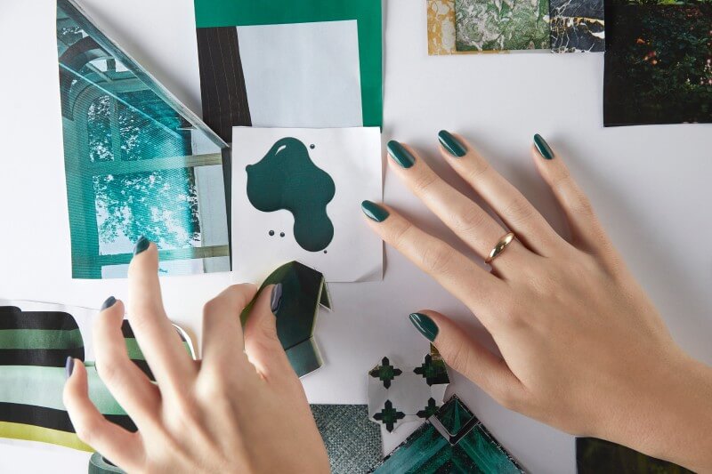 Person with dark green nails pinning photo to board