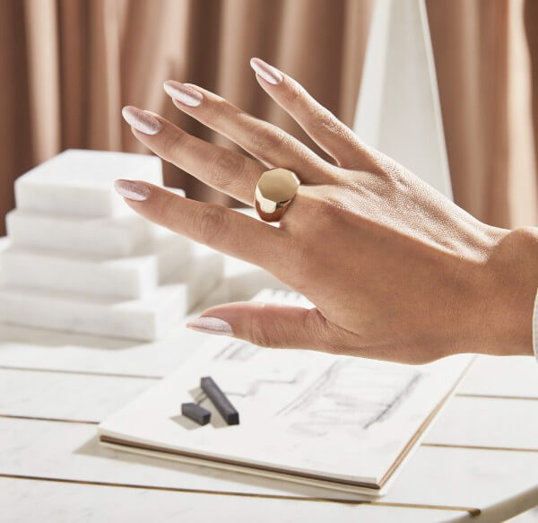 Hand with gold ring shows gold shimmery nails