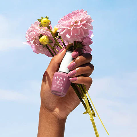 Hand Holding Pink Flowers and OPI Nature Strong Vegan Nail Polish 