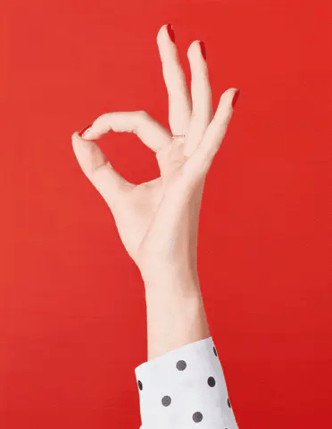 A hand with red nails and polka dotted sleeve against red background