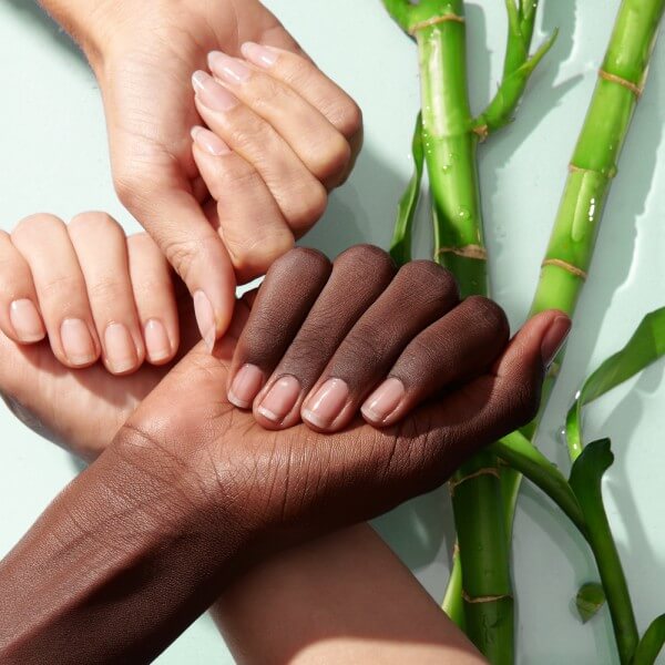 three hands in loose fists show natural nails next to bamboo