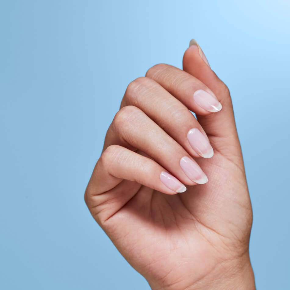 Hand showing naturally healthy nails with blue background