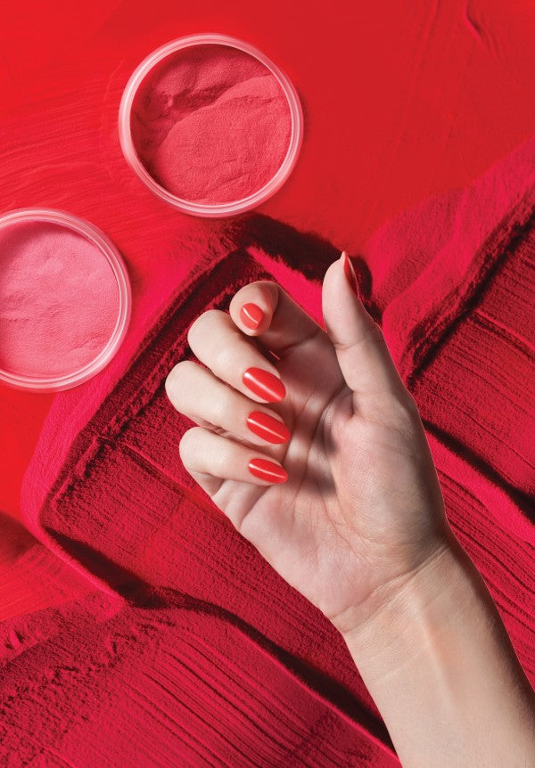 Hand with red nails above a red powder background