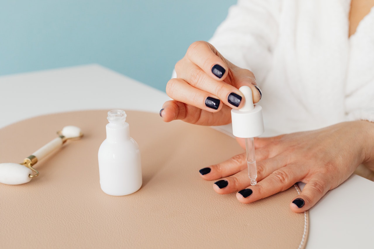 Person Applying Clear Cuticle Oil on Nails With Black Polish