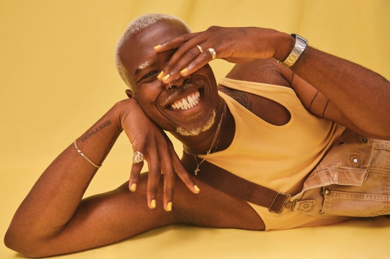 Person poses in yellow outfit showing off yellow nails