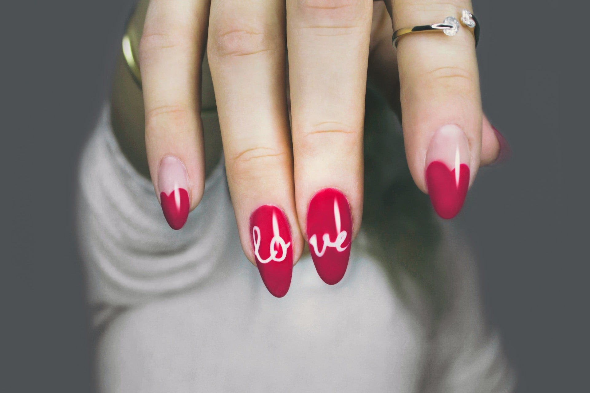 Picture of Hand With Red Polish and “Love” Written in White Letters 