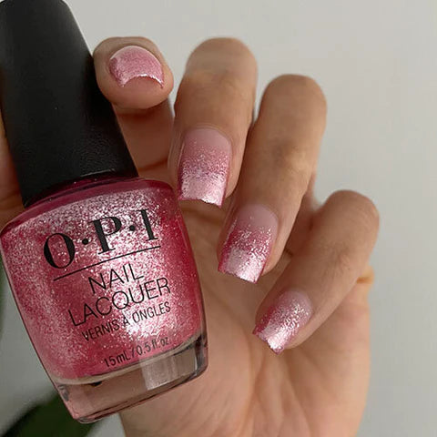 Pink glitter nail art on hand holding OPI nail lacquer bottle