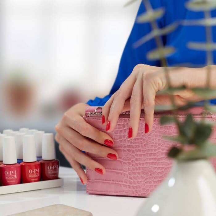 woman zips up purse with fresh red nails