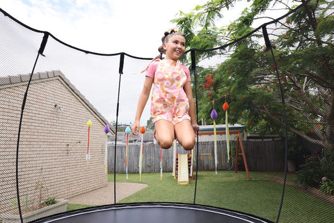 A girl smiling while jumping on a trampoline.