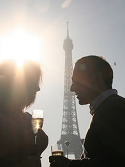 A couple enjoying a glass of champagne under the Eiffel Tower in Paris.