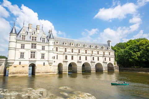 Two people in a row boat in front of Chenonceau castle in the Loire Valley, France.