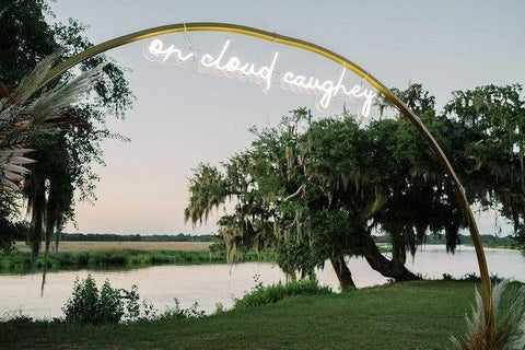 Neon sign reading "on cloud craughey" on an arch overlooking a serene lakeside