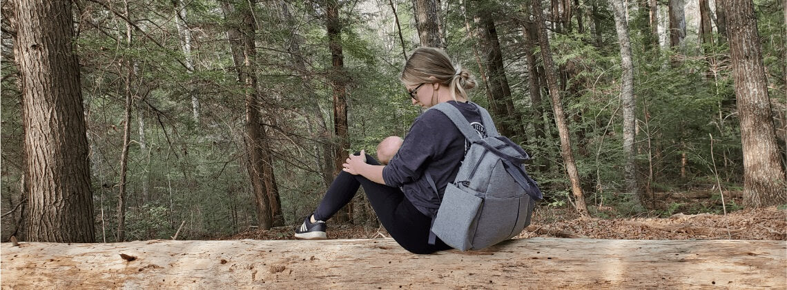 Woman breast feeding baby in the woods