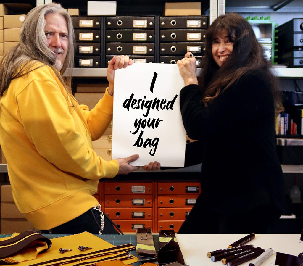 Bertrand Rigot and Marion Verbucken from eKodoKi, in their studio, jokingly pretending to fight over a sign stating "I designed your bag"
