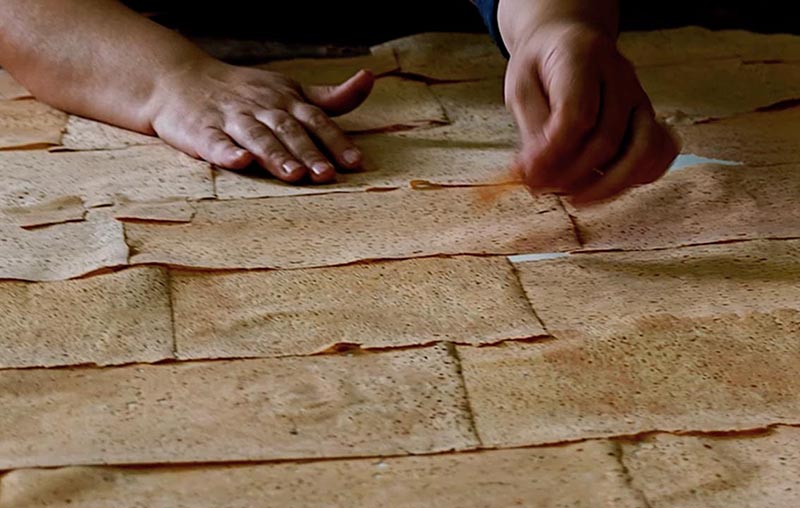 Foto von dünnen Korkplatten, die von Hand auf ein Trägergewebe gelegt werden.