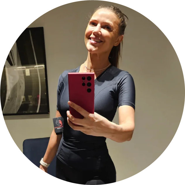 Person taking a mirror selfie with a red phone, wearing athletic clothing.