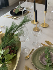 Kerststukje op tafel met gouden kandelaars