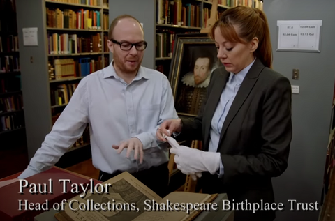 screengrab from BBC's "Cunk on Shakespeare" showing the host, Philomena Cunk and Paul Taylor, Head of Collections, looking at a book.