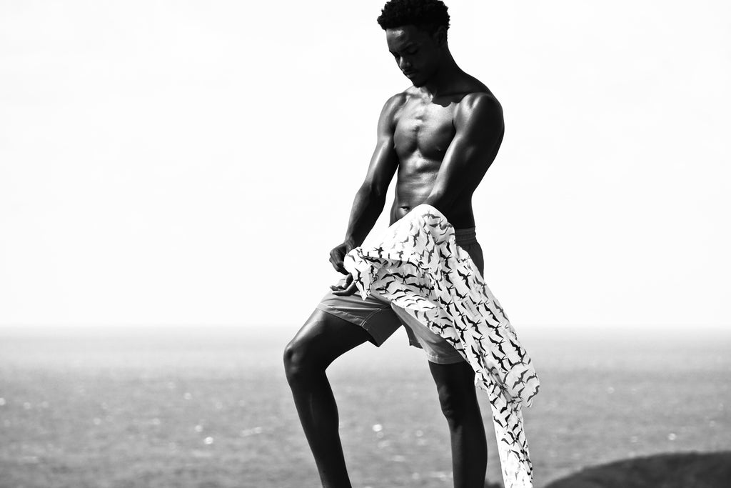 black and white photo of mans leg next to sea