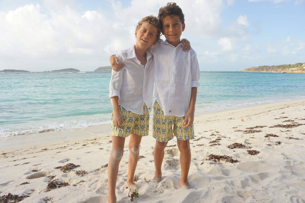 Boys hugging on the beach in Beetle swim shorts