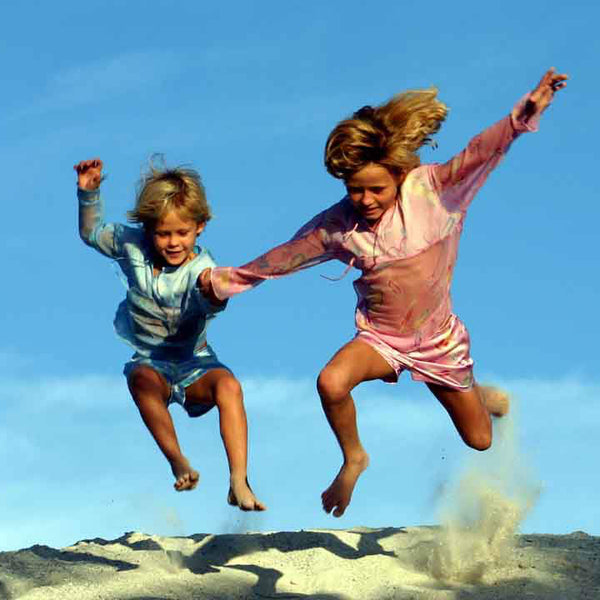 Sisters jumping in the sand, Mustique island, photographed by Lotty B