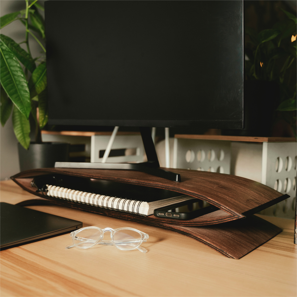 wooden monitor stand in brown color on desk with monitor and other office supplies