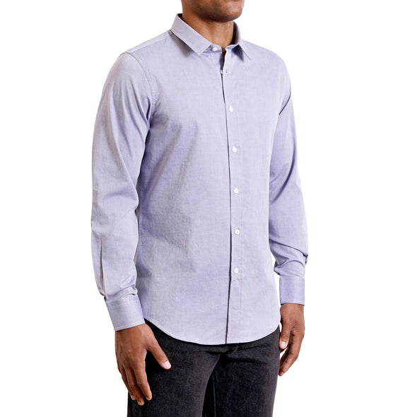 Three quarters side view of men's long sleeve, slim fit, classic blue button up shirt on a black model. Organic cotton fabric has a small diamond pattern woven into it.