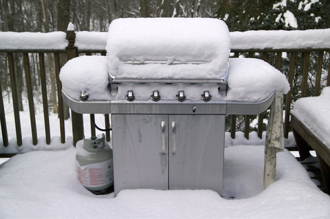 Stainless steel grill in the snow sitting on the backyard deck