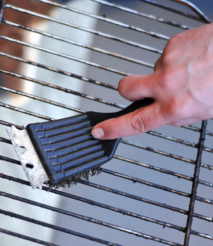 Man Using a Wire Grill Brush to Clean Stainless Steel Grill